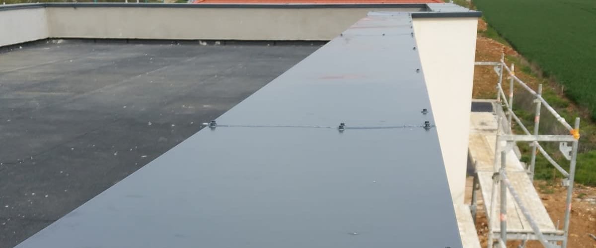 Couvertine en acier laqué gris posée sur l'acrotère d'une toiture-terrasse, échafaudage en façade