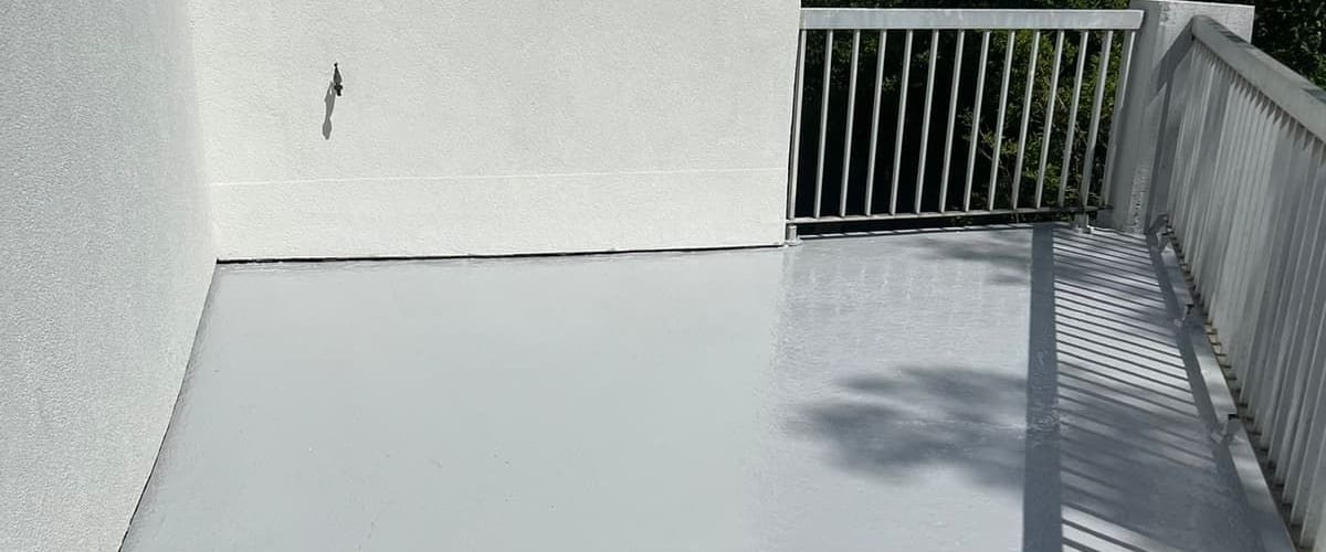Balcon étanché à la résine liquide grise, relevés en pied de façade et garde-corps métallique