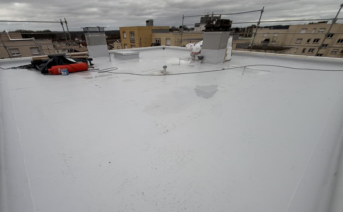 Toiture-terrasse refaite en membrane claire, sorties de ventilation relevées, immeubles en arrière-plan