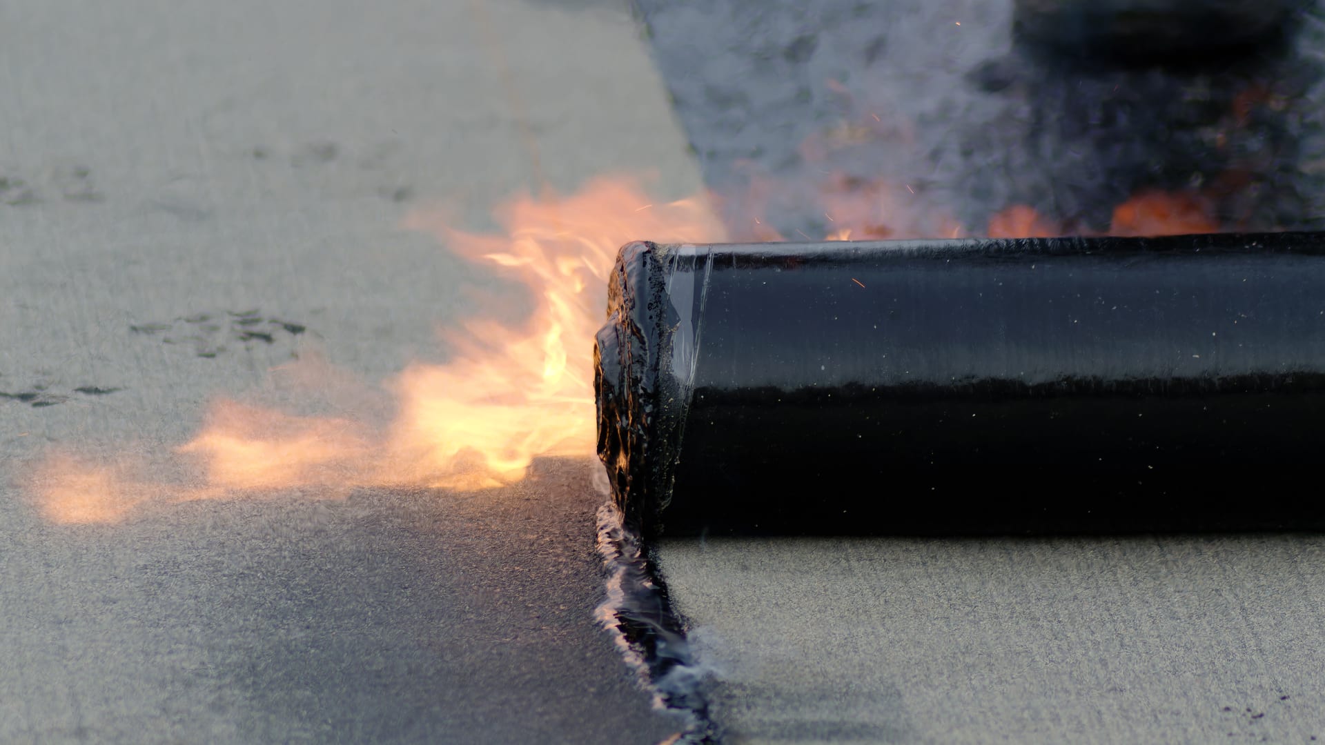 Soudure au chalumeau d'un rouleau de bitume sur une toiture-terrasse